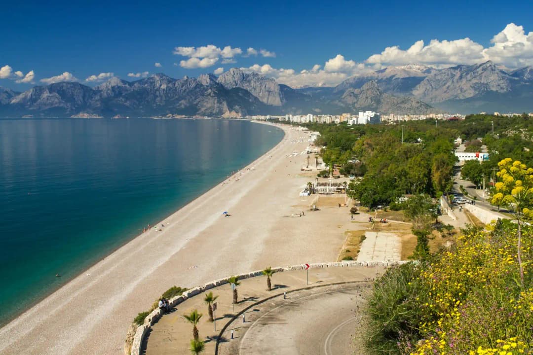 A panorama of the Mediterranean beach with mountains in the background of Antalya
