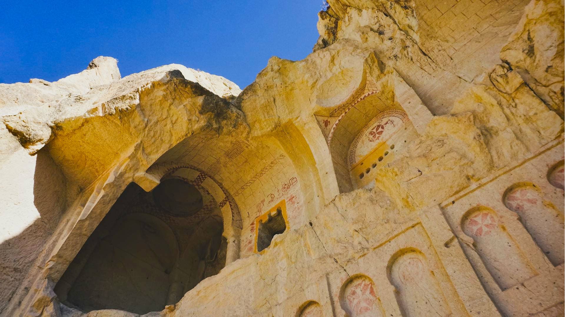 A cave church adorned with Maltese Crosses applied on the soft tufa rock using red ochre painting.